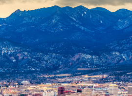 distance shot of the skyline of Colorado Springs with snowy mountains in the background