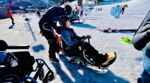 male youth sitting in a sit-ski all bundled up