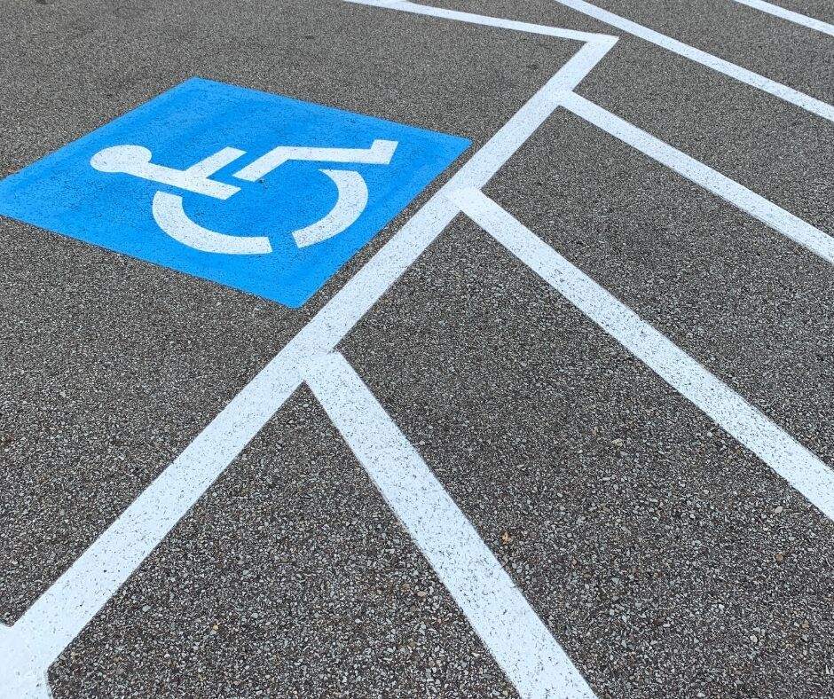 blacktop parking lot space with blue and white accessible symbol and parallel access lane lines