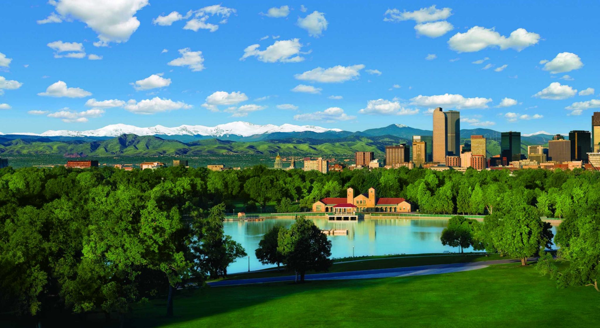 City park lake in the foreground. distance shot of the skyline of Denver with the snowcapped mountains in the background
