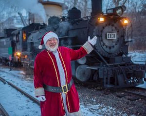 adult male in Santa suit in front of a black steam engine #491