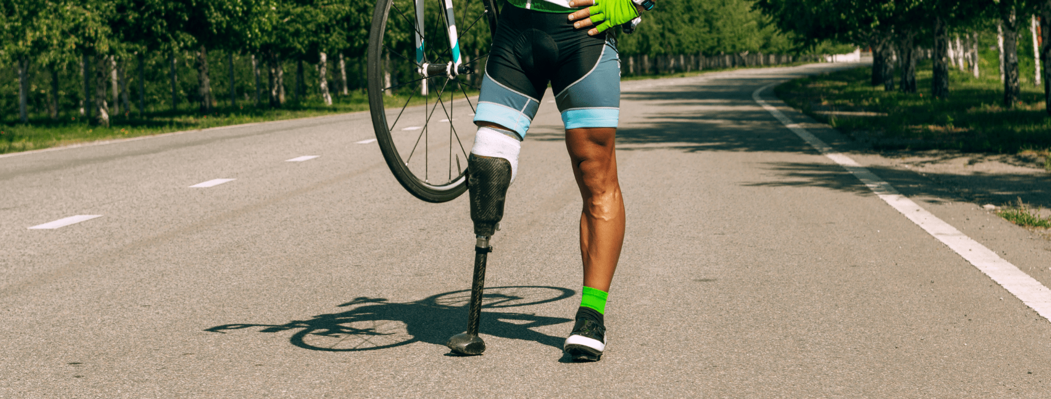 male with a prosthetic right leg holding a bicycle