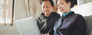  senior asian couple sitting on a couch with laptop.png