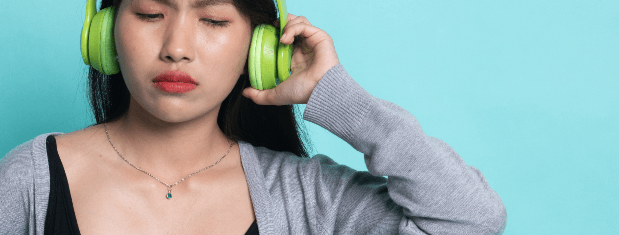 asian woman with green headphones on with a distressed look woman