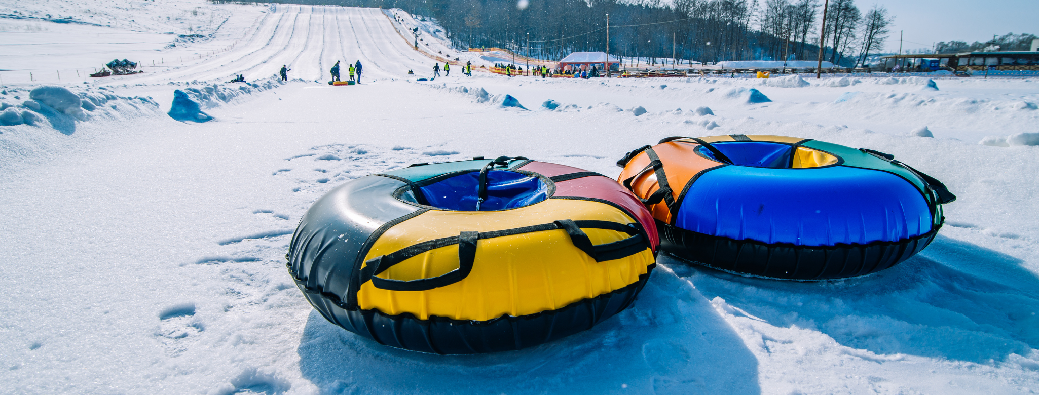 two multicolored sledding tubes at the bottom of a hill