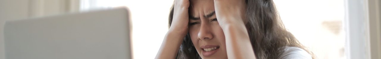 latinx female looking at a laptop and grabbing her hair with a look of frustration